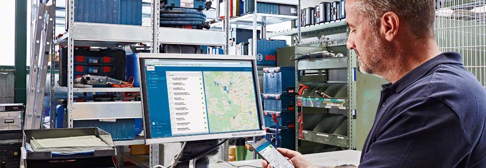 Person am Computer mit Smartphone